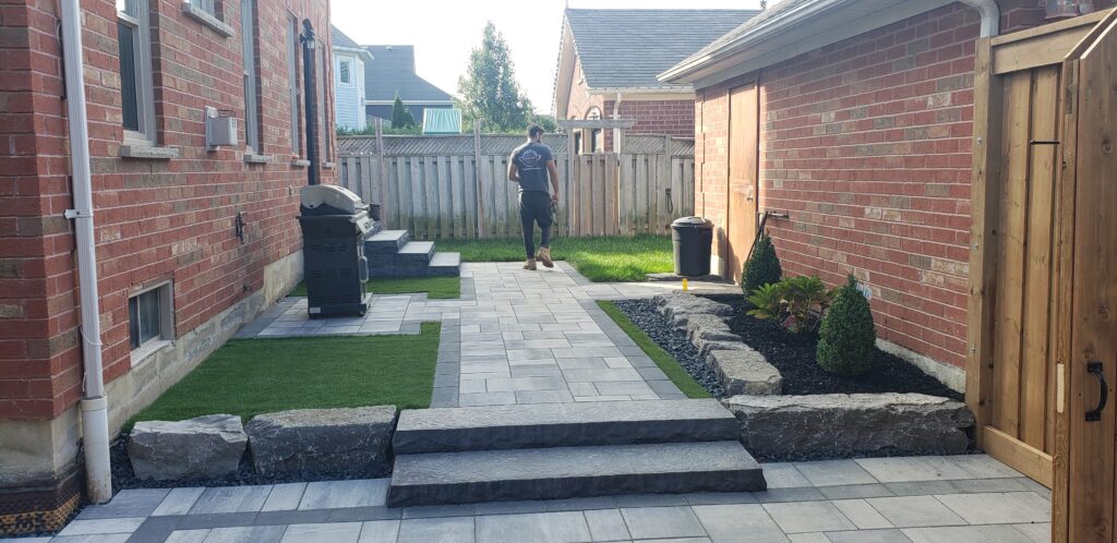Backyard transformation with Trevista Carrara pavers, Onyx borders, natural stone steps, and artificial grass in Newmarket