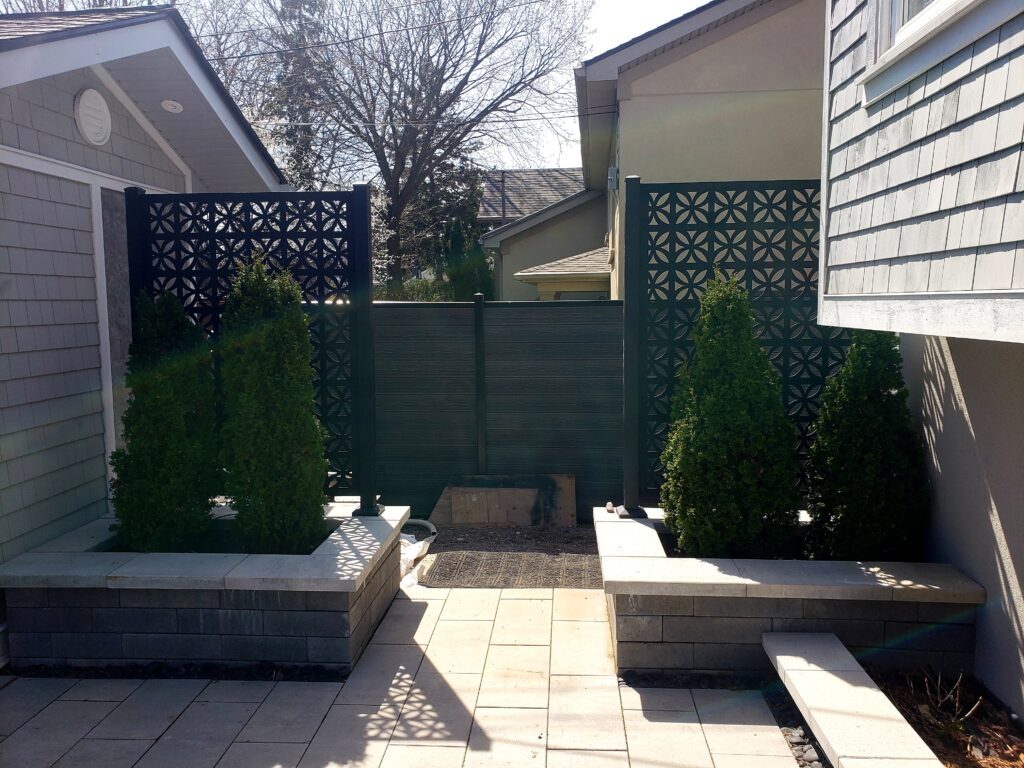 Two mirrored backyard flower beds at the entrance featuring Permacon Urbano walls in Shaded Grey, topped with Permacon Melville Scandina Grey straight caps. Serving Newmarket