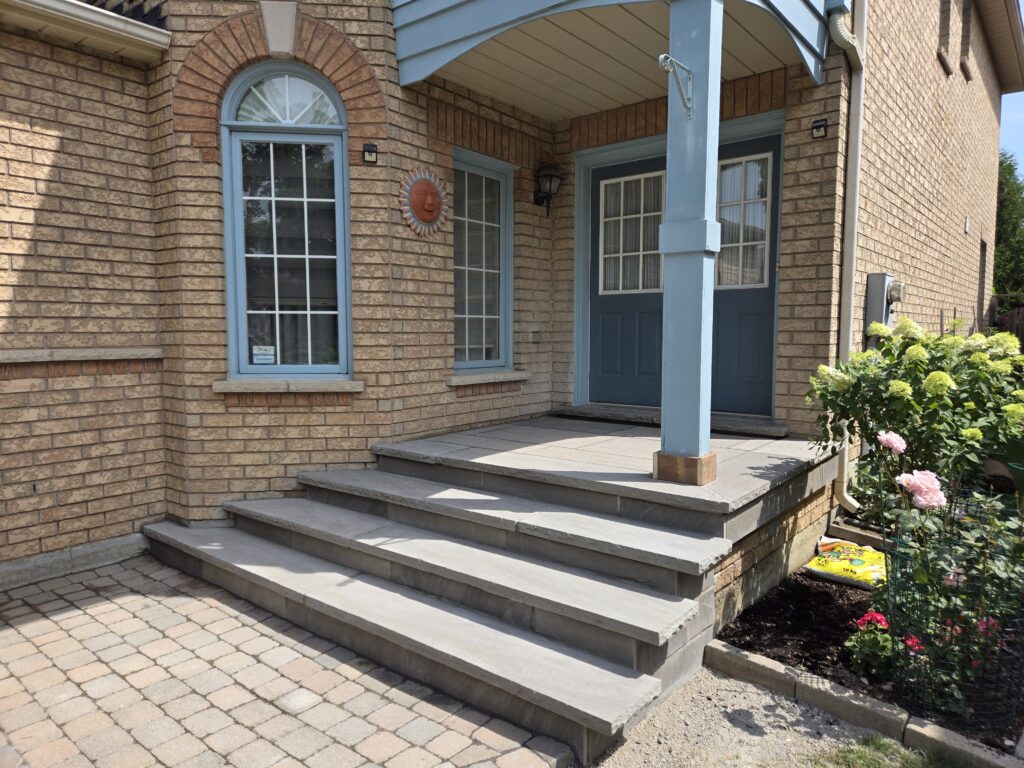 Three custom concrete steps with slate grey rock-faced coping, a flagstone porch and risers, and slate grey coping on the door sill landing, installed in Aurora, Richmond Hill, Markham, Stouffville and Newmarket
