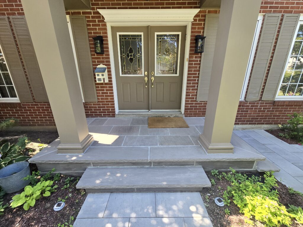 Newmarket natural Slate Grey stone front porch with 2-inch rock-faced coping on the steps and porch perimeter, finished with 1-inch Slate Grey flagstone on the porch landing and step faces.