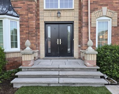 Two custom poured concrete steps with 1 ft deep slate grey coping, rock-faced hand-chiseled edges, and slate grey flagstone on the porch and risers