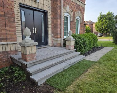 Two custom poured concrete steps with 1 ft deep slate grey coping, rock-faced hand-chiseled edges, and slate grey flagstone on the porch and risers