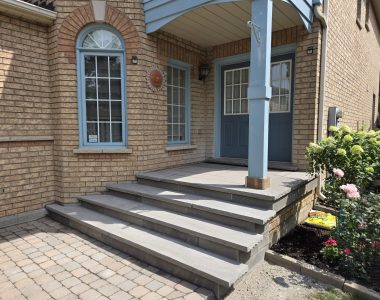 Three custom concrete steps with slate grey rock-faced coping, flagstone porch and risers, and slate grey coping on door sill landing