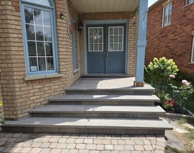 Three custom concrete steps with slate grey rock-faced coping, flagstone porch and risers, and slate grey coping on door sill landing